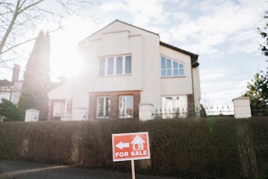 A modern home with a “For Sale” sign in the front yard